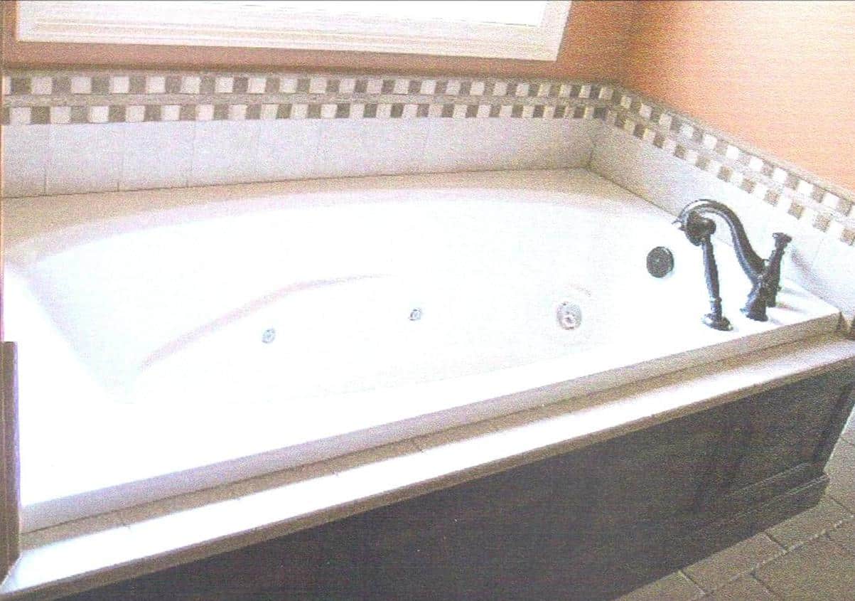 Gibson Design Group Inc. bathroom remodel featuring a jetted bathtub with tiled backsplash and bronze faucet in Grosse Pointe, MI.