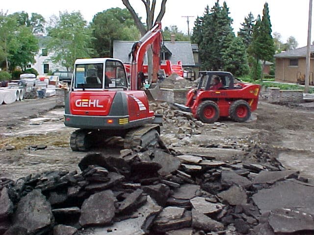 Gibson Design Group Inc. heavy equipment excavation with skid steer and excavator preparing residential driveway in Metro Detroit.