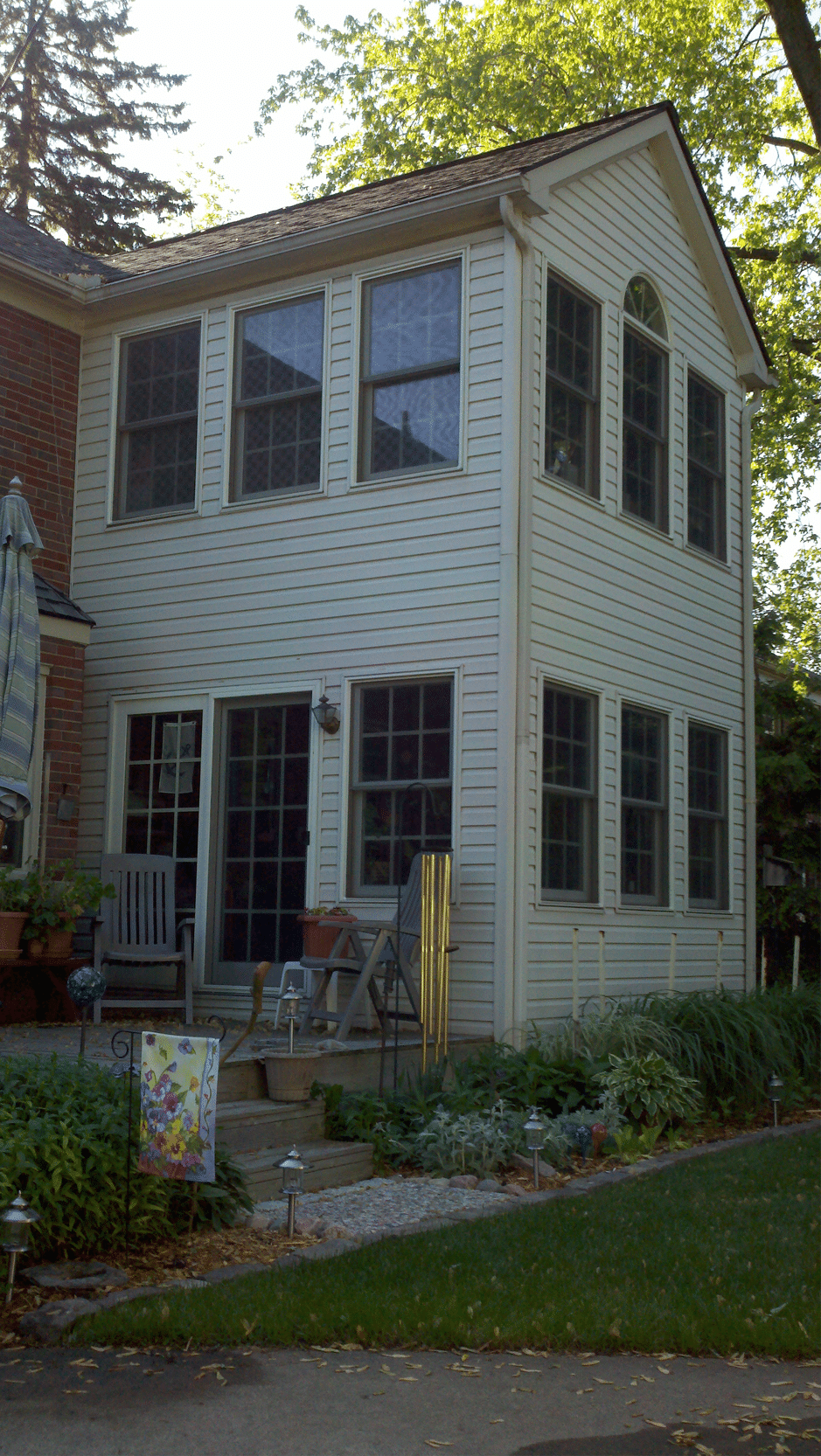 Gibson Design Group Inc. two-story home addition with large windows and backyard patio in Metro Detroit.
